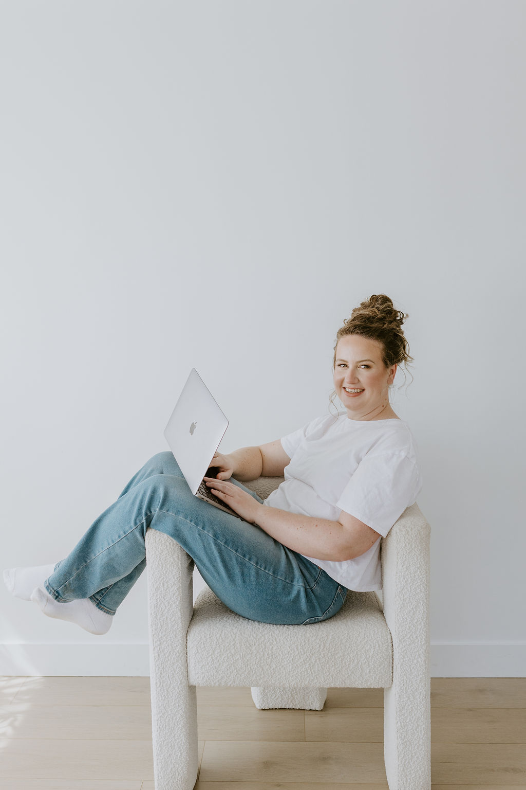 Megan working from a boucle chair, laptop on her knees.